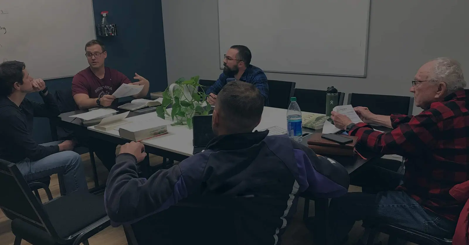A group of men are sitting around a table having a discussion in a meeting room.