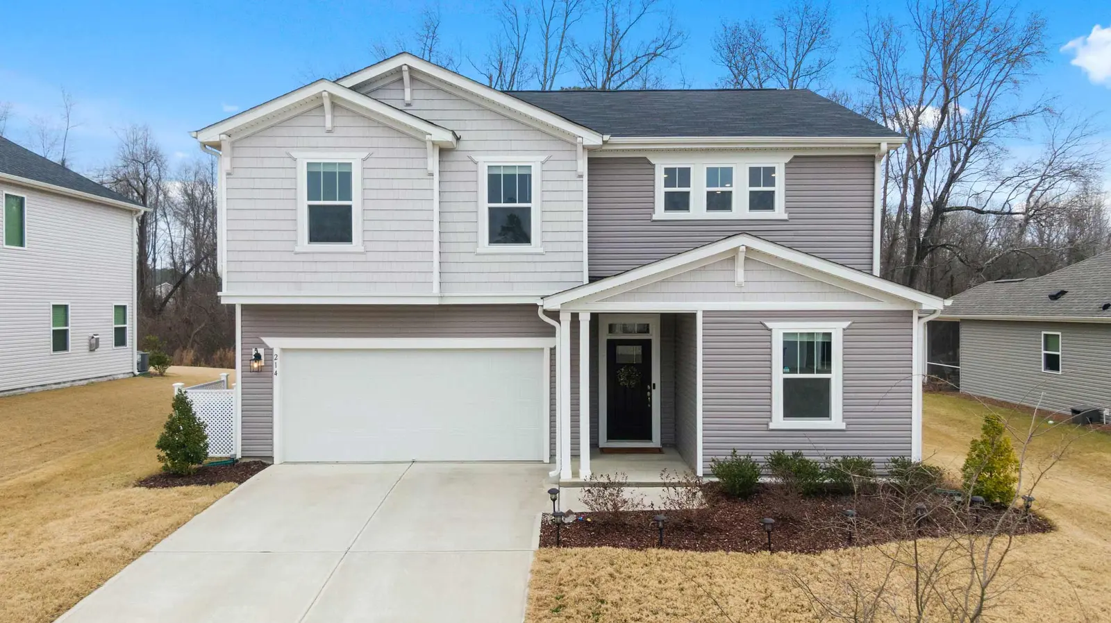 A two-story suburban house with a grey and light grey facade and a concrete driveway.