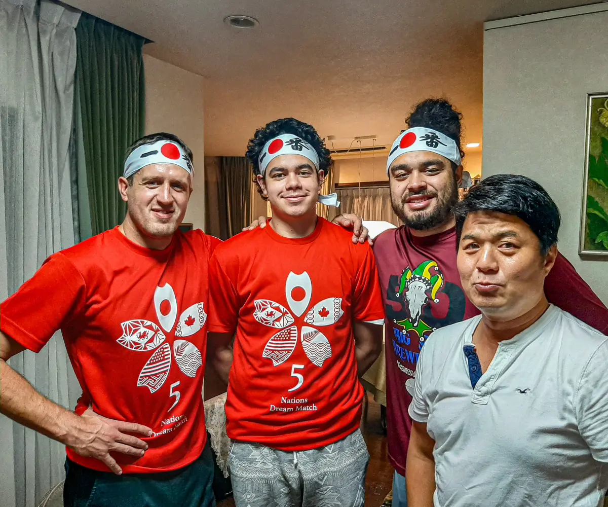 A group of four men pose together indoors.