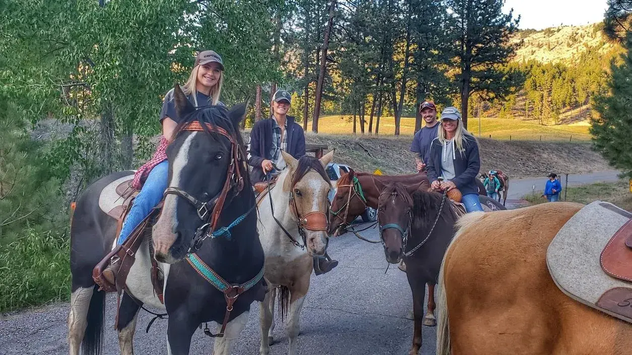 A group of adults riding horses on a trail outdoors.