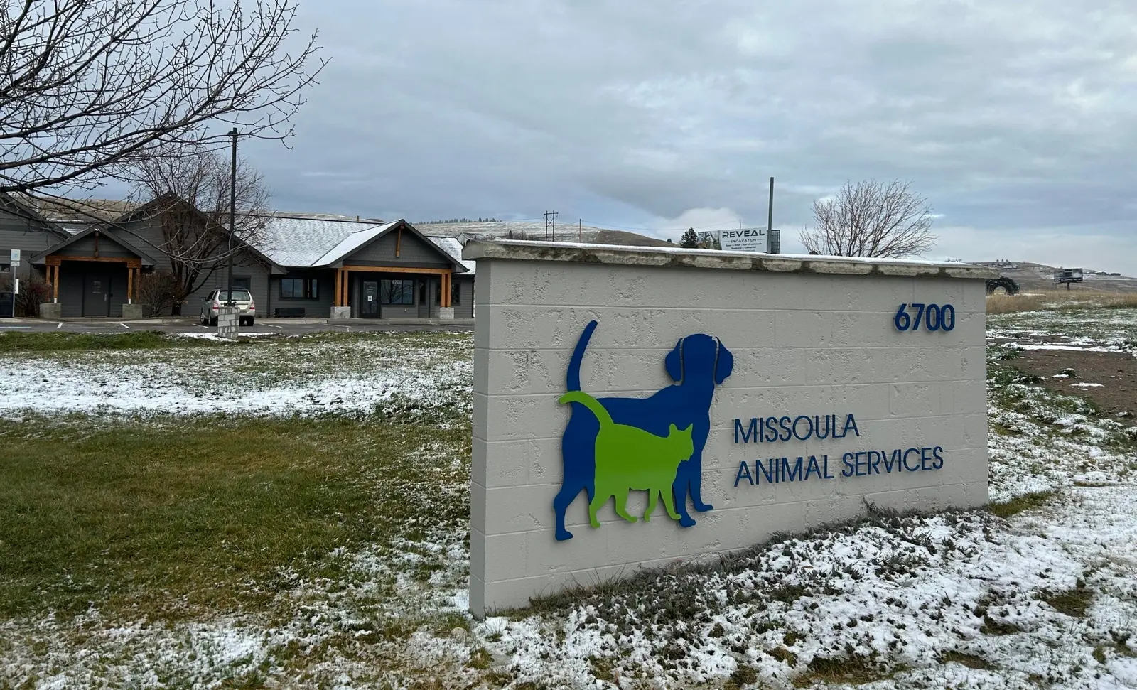 A view of a building with a large sign in the foreground featuring a dog and cat icon.