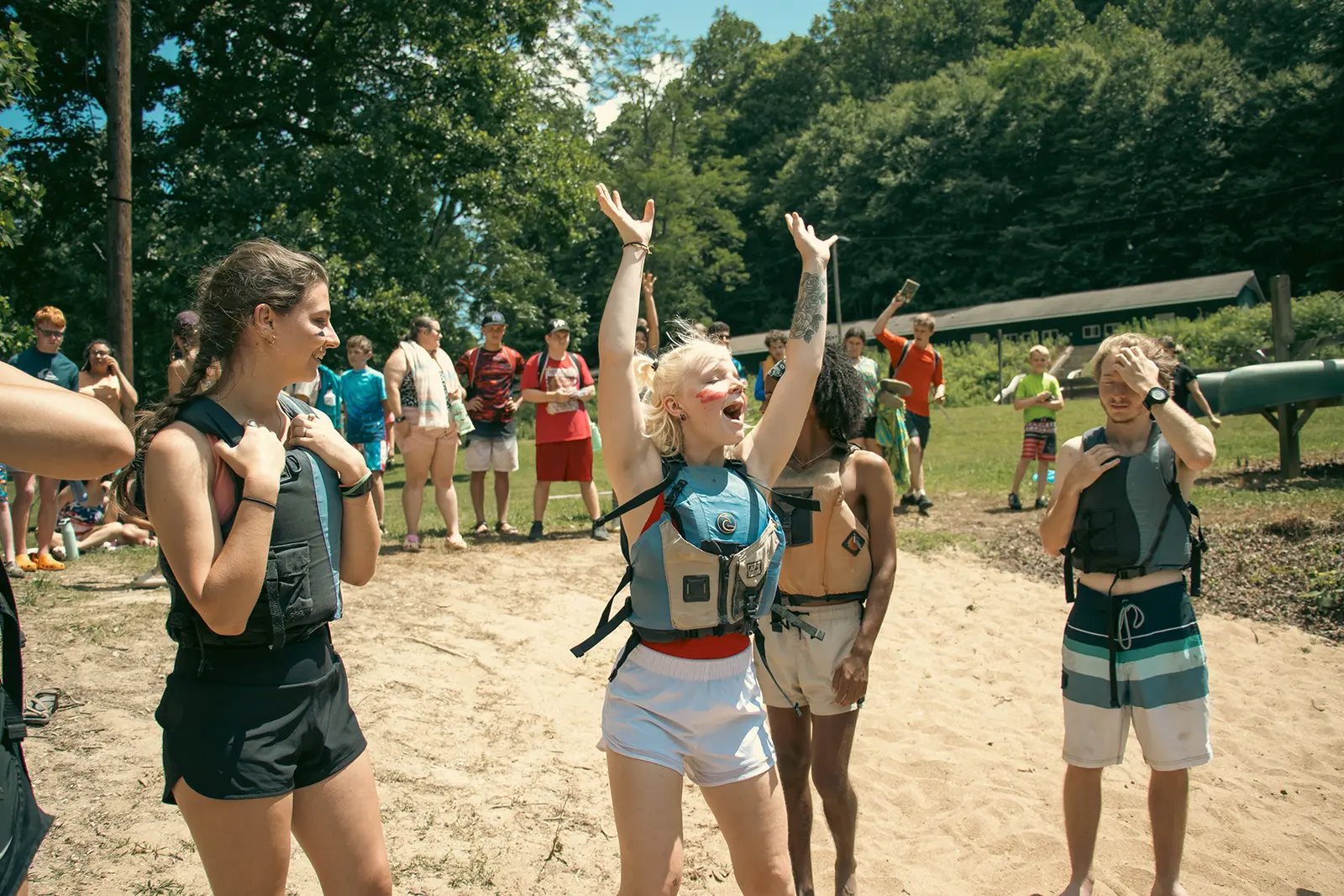 A group of young people gathered outdoors wearing life vests.