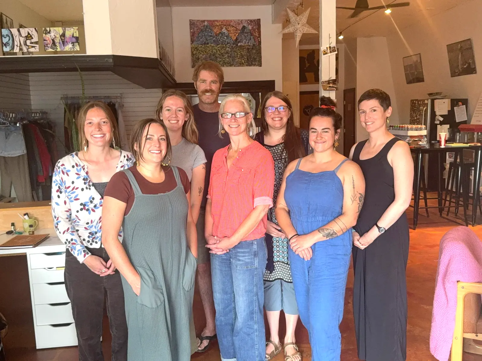 A group of eight adults poses together indoors.