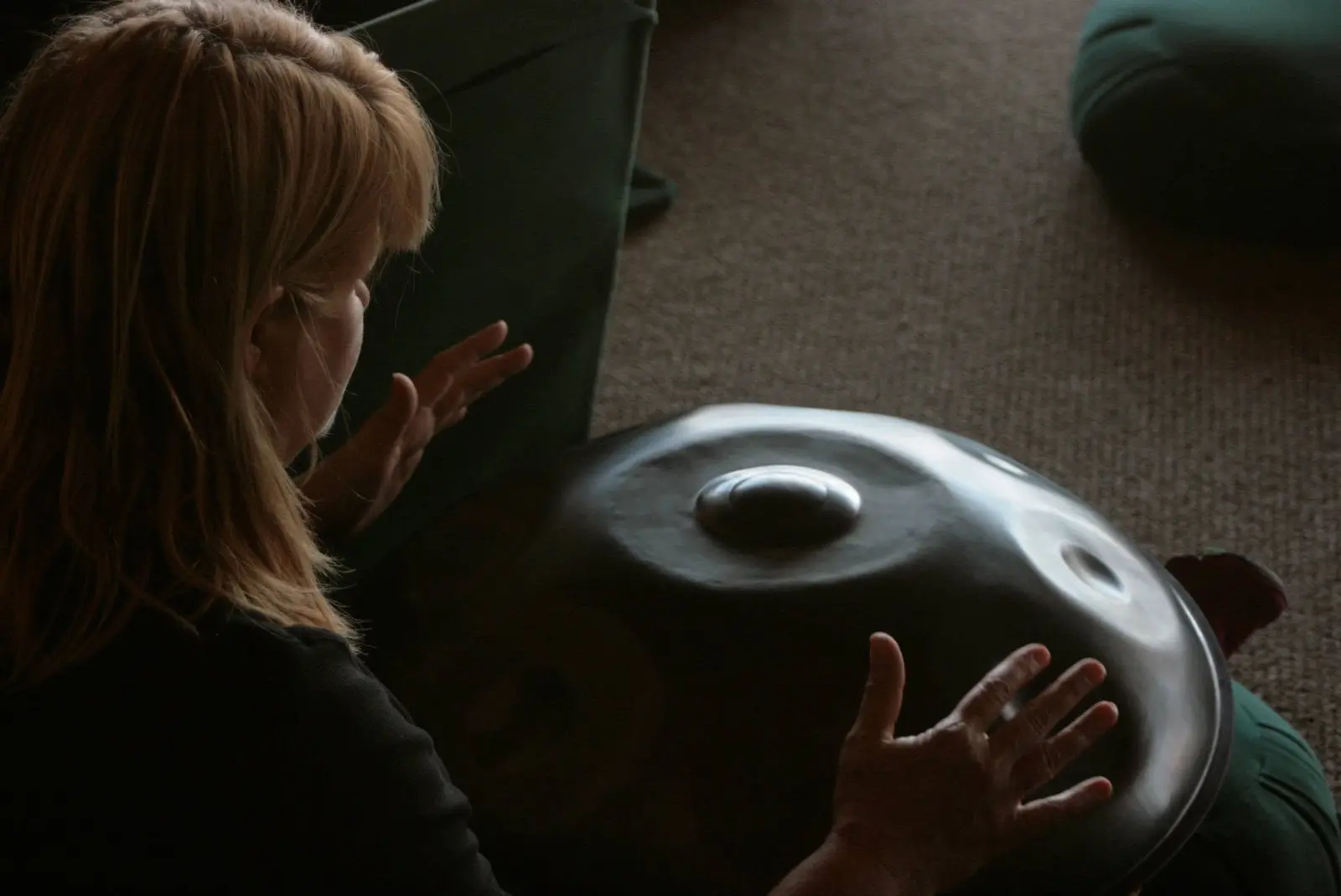 A person plays a metallic handpan instrument.