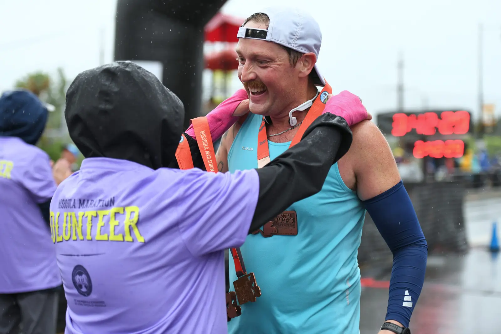 A volunteer places a marathon medal around the neck of a runner after a race.