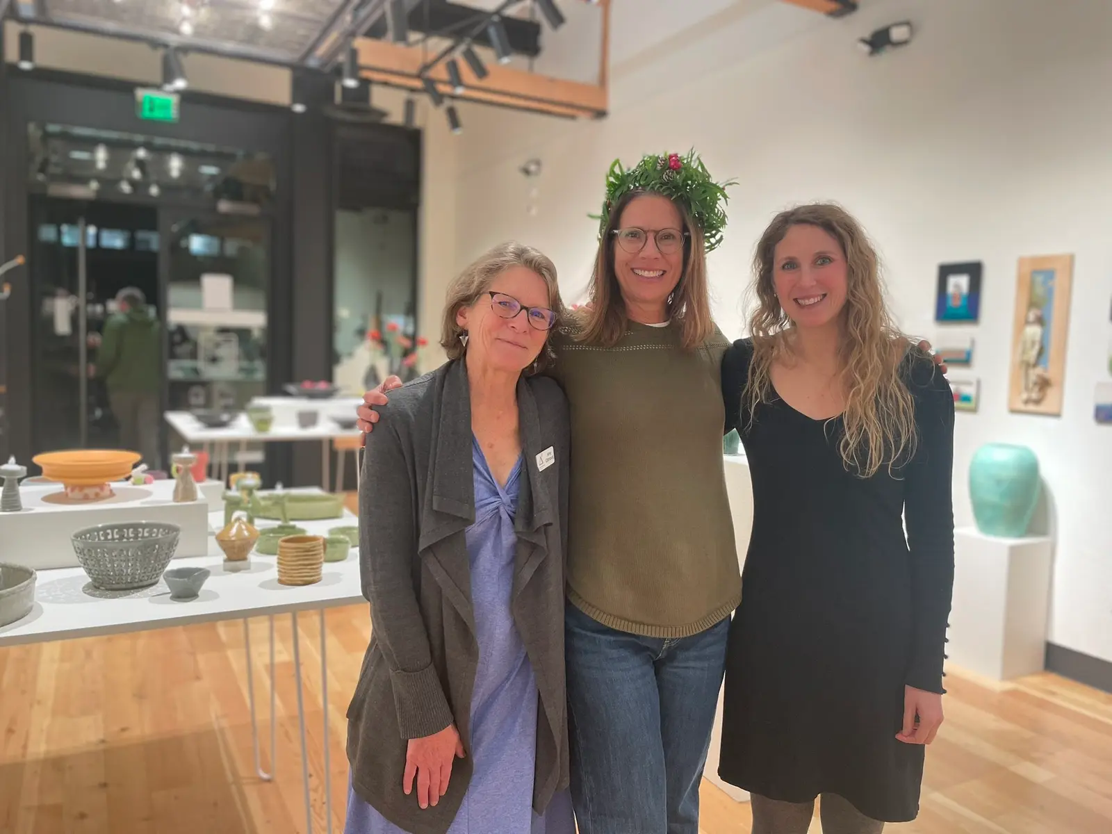 Three women stand together in an art gallery.