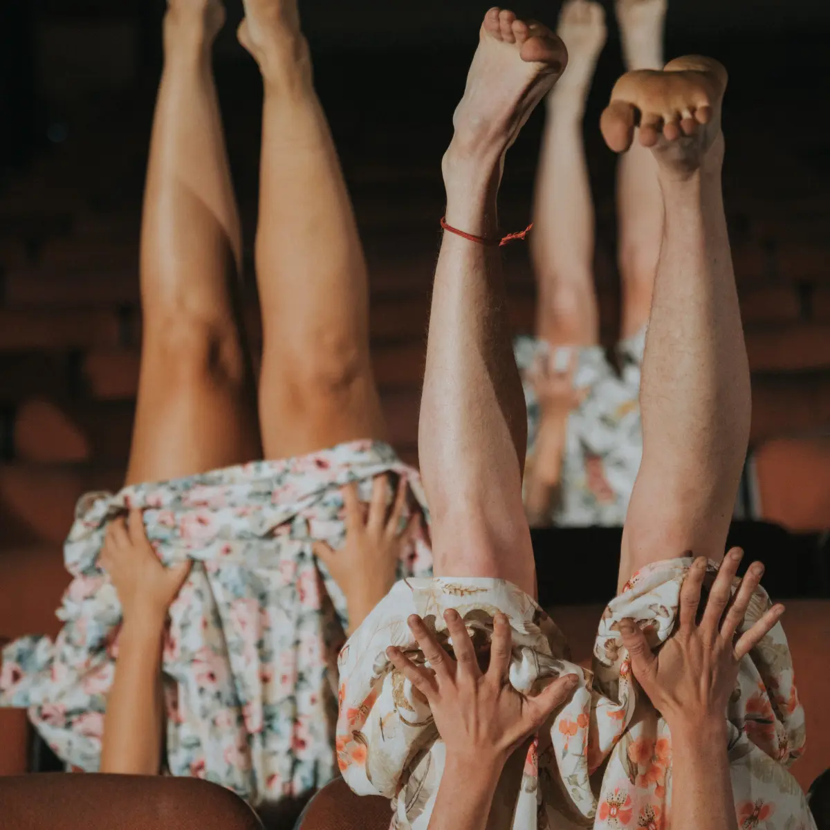 Two people wearing floral outfits have their legs raised in the air.