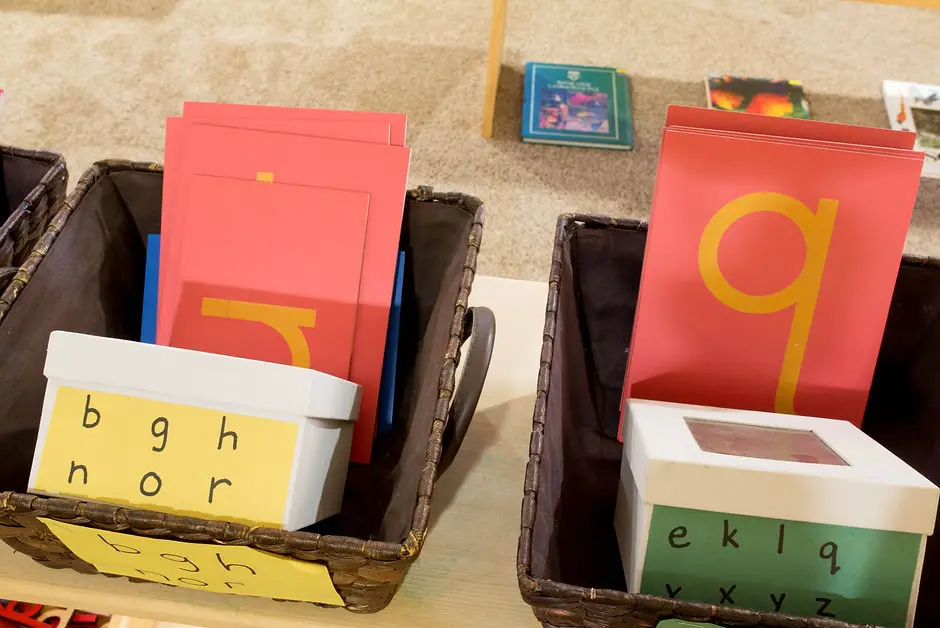 Two baskets filled with alphabet learning materials and letter cards sit on a surface.
