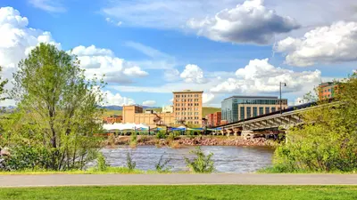 Photo from nbcmontana.com A city skyline and bridge overlook a flowing river under a partly cloudy sky.