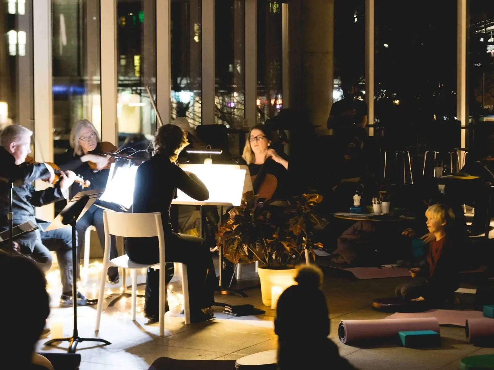 A musical ensemble performs in a dimly lit space while an audience listens.