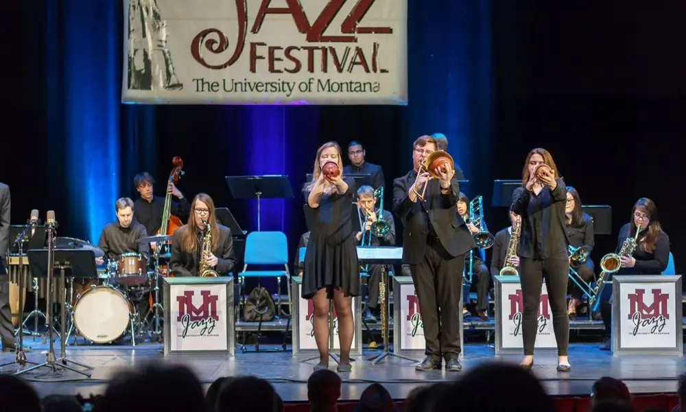 A jazz band performs on a stage under a banner.