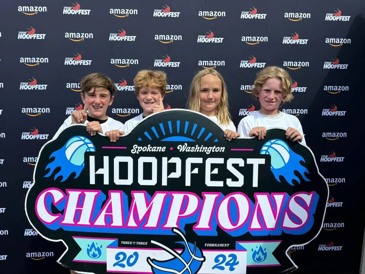 Four kids proudly hold a Hoopfest Champions sign.