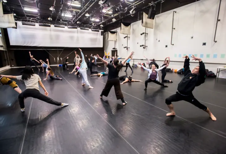 Dance technique class performing expressively with the instructor in the middle