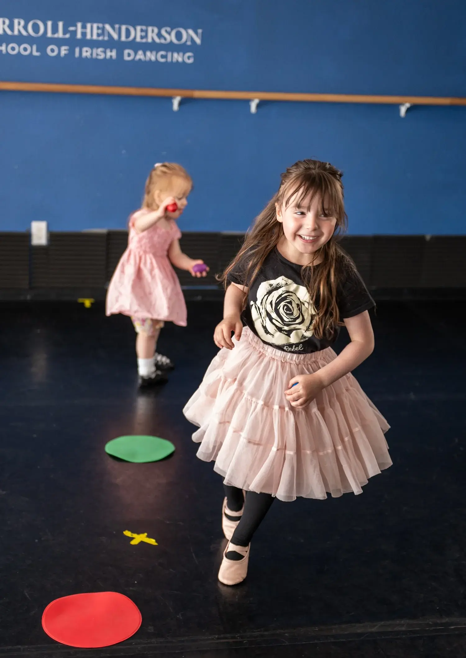 Two young girls are active in a dance studio.