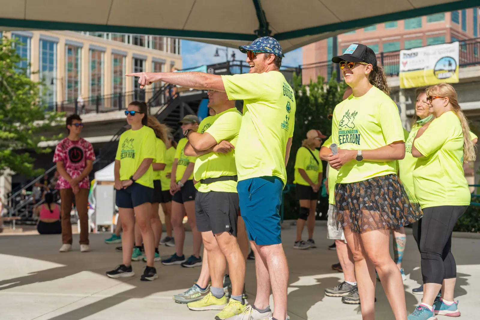 A group of people wearing bright yellow shirts participate in an outdoor event with an instructor pointing.