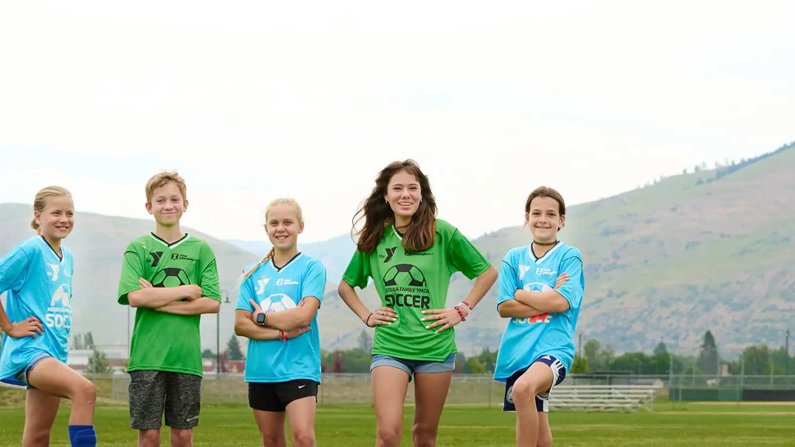 two teen soccer players in green jerseys and two players in blue jerseys during a missoula ymca soccer practice