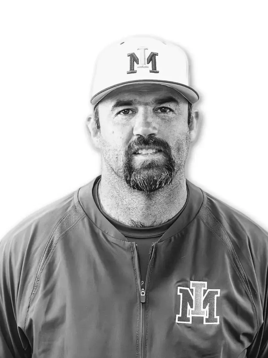 A man with a goatee wearing a baseball cap and jacket featuring the same emblem is shown in a portrait.