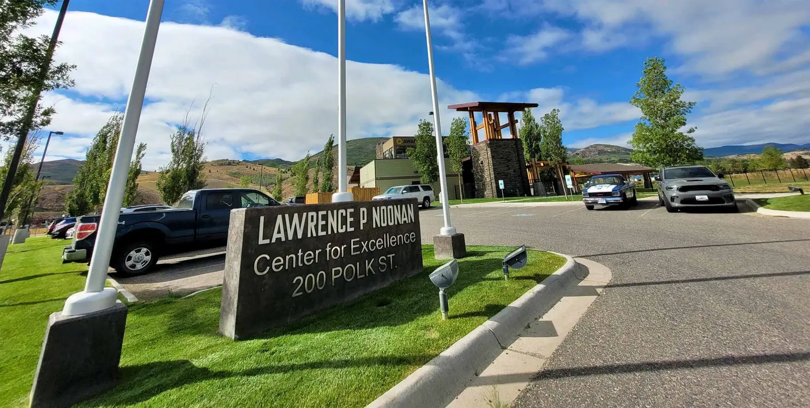 A stone sign stands in front of the Lawrence P Noonan Center for Excellence building.
