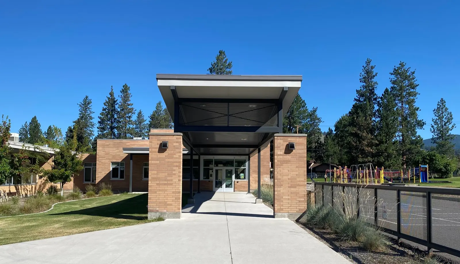 A view of the entrance to a school building with a playground visible in the background.