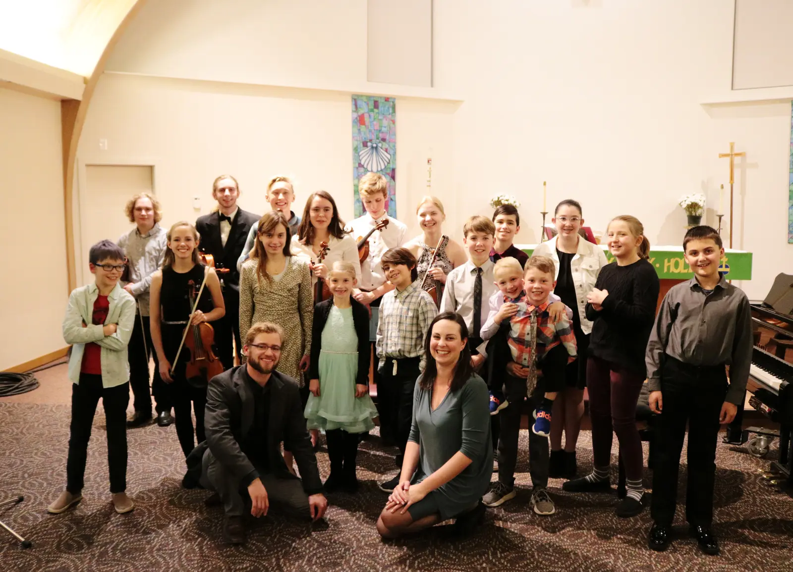 A group of children and two instructors pose for a photo in an indoor setting.