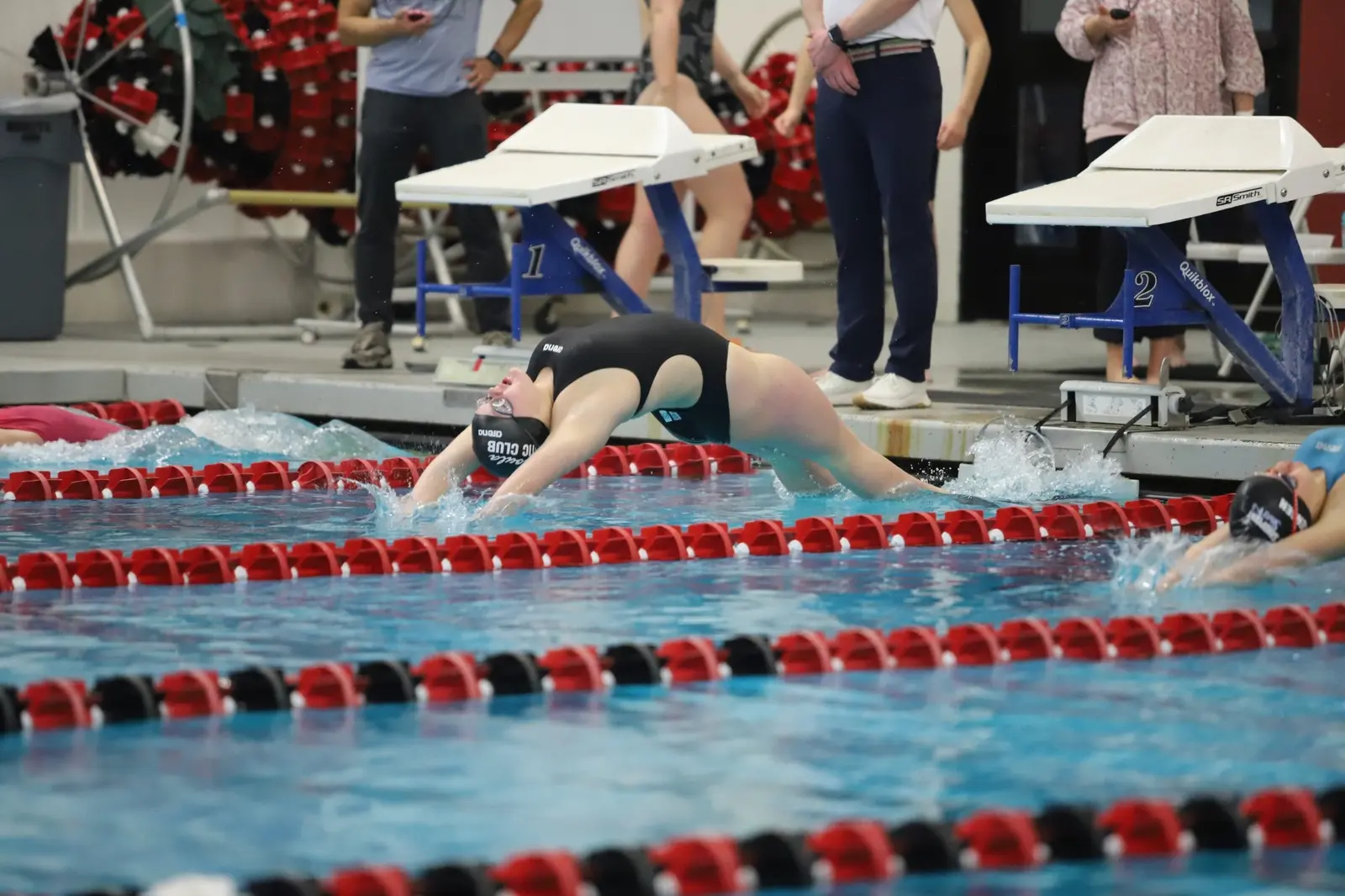 A swimmer performs a backstroke start in a pool during a competition.