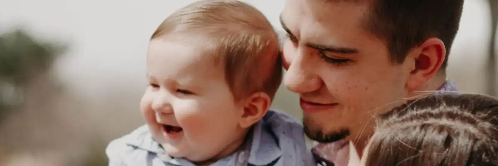A smiling parent holds a baby close.