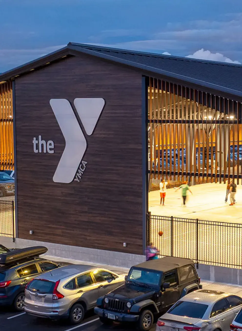 an aerial view of the missoula ymca's covered outdoor basketball court. a group of people play basketball in the open-air structure