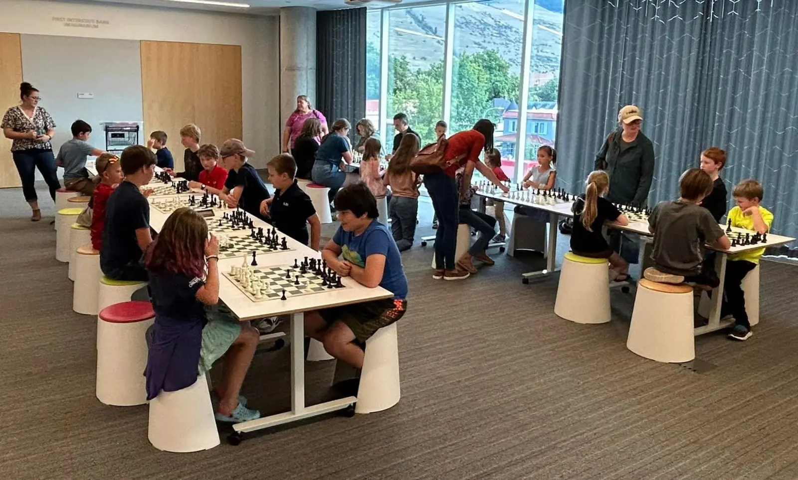 A group of children actively participate in a chess tournament at a community facility.