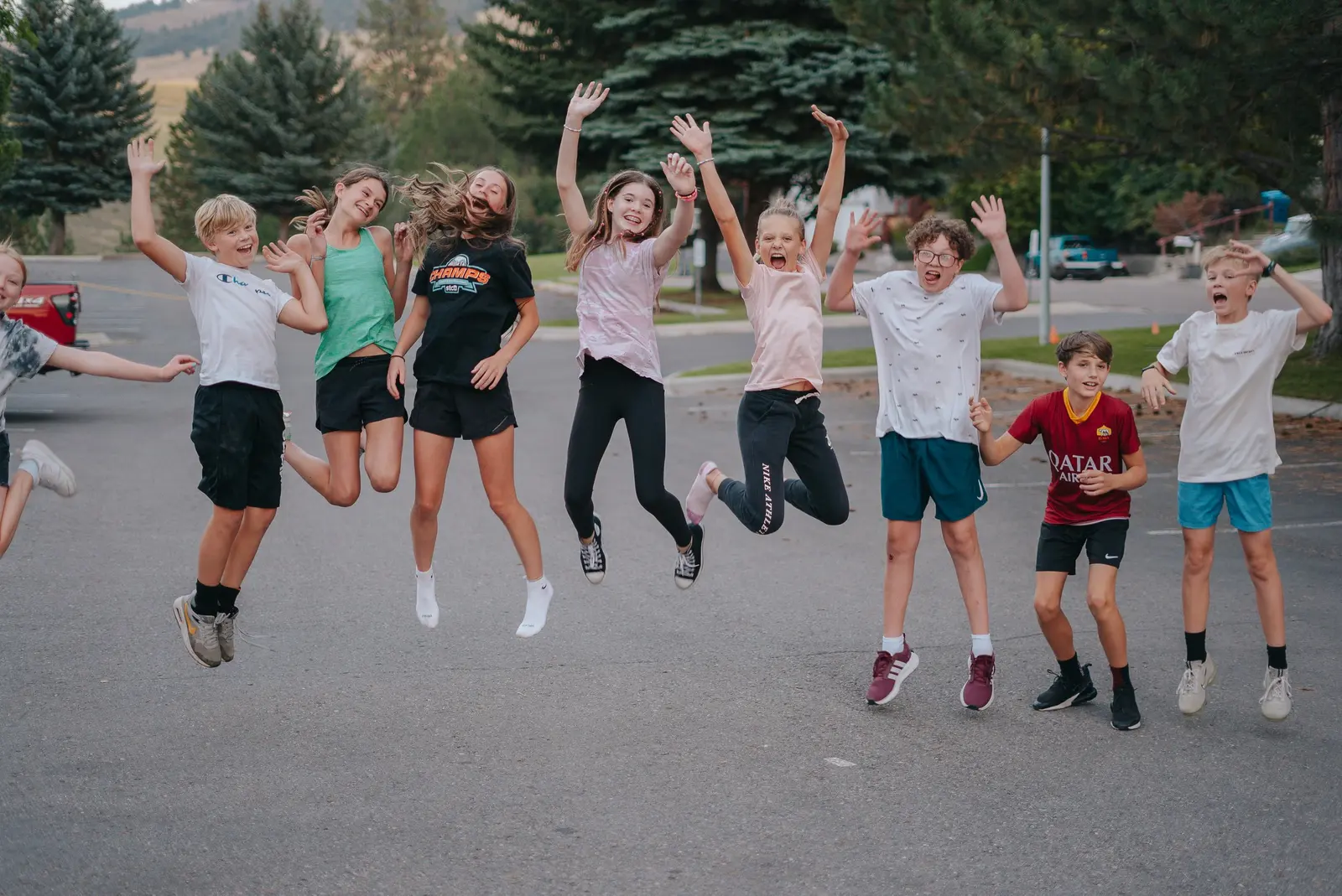 A group of children jumping in the air in a parking lot.
