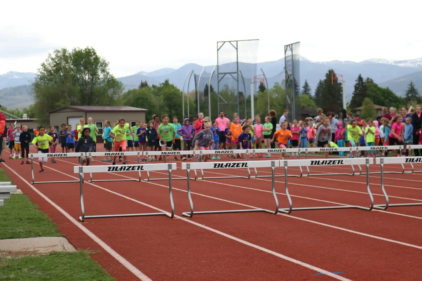 A group of children participate in a hurdle race on a track.