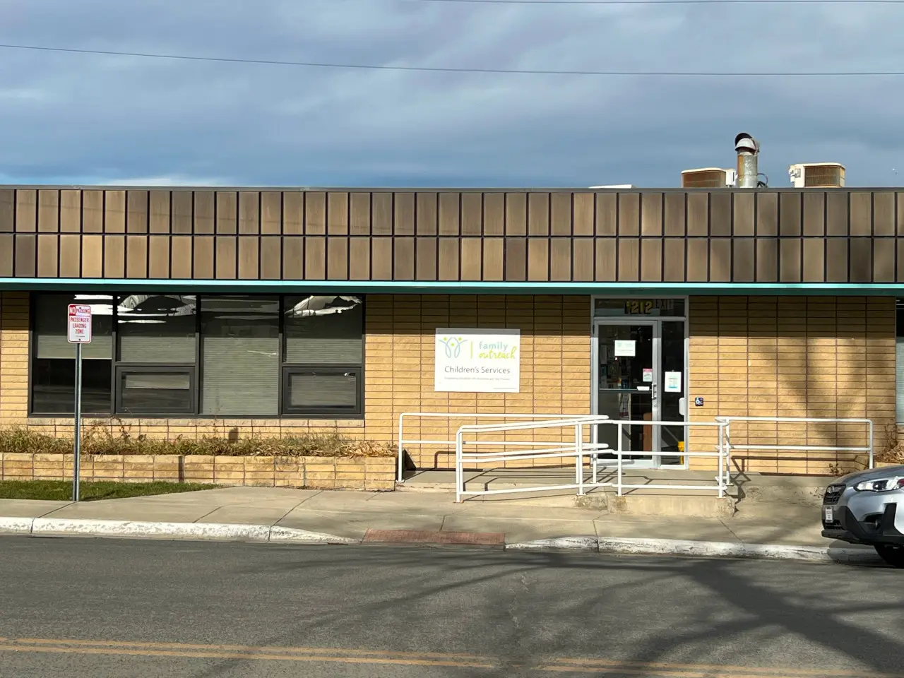 A view of a building exterior with a sign for family outreach and children's services.