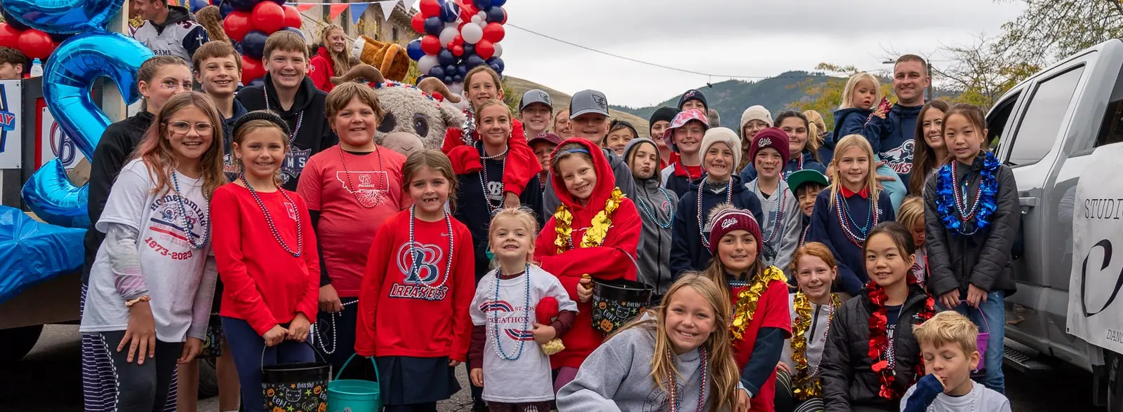A large group of children and some adults posing in front of a parade float.