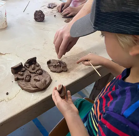 A child works with clay on a table with guidance.