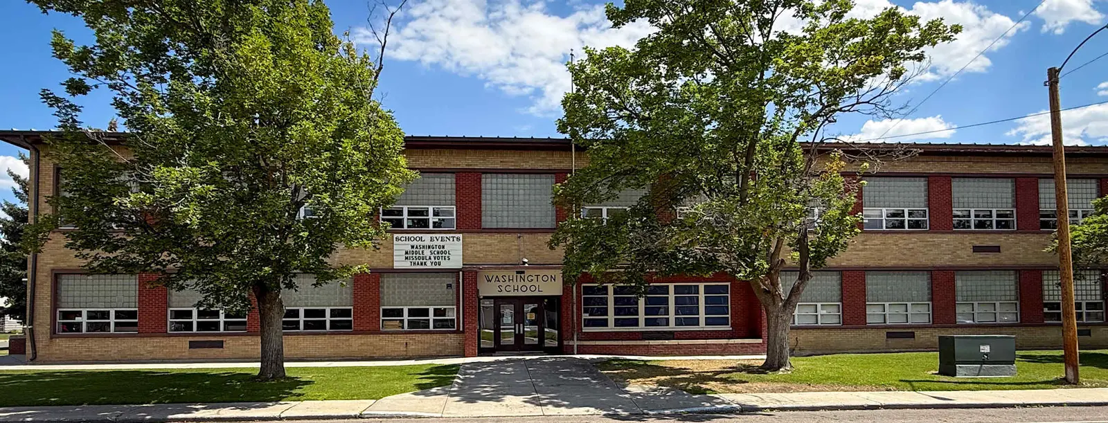 A brick school building stands under a bright blue sky.