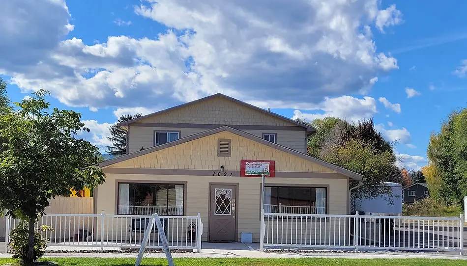 A tan building with a white fence stands under a cloudy blue sky.