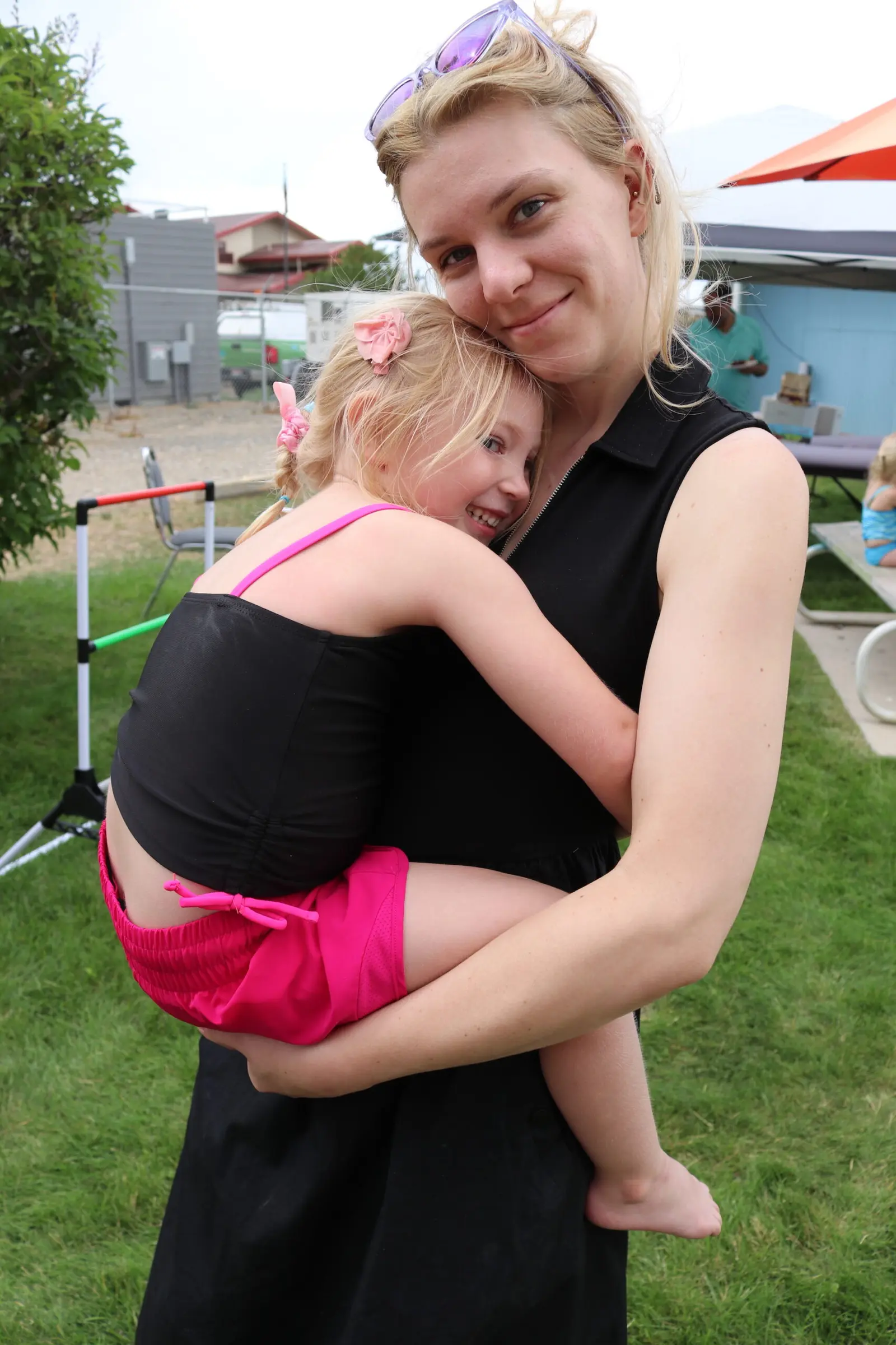 A woman is holding a young girl in her arms outdoors.