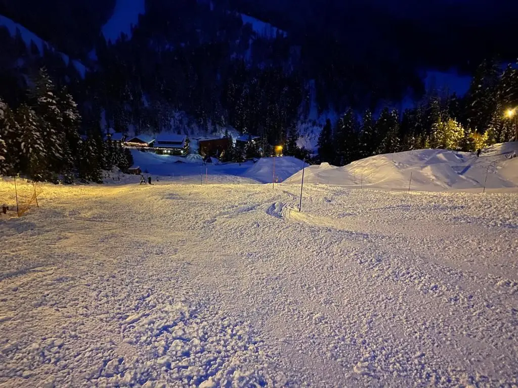 A view of a snow-covered ski slope illuminated at night.