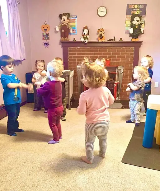 A group of young children are playing and standing together in a room.