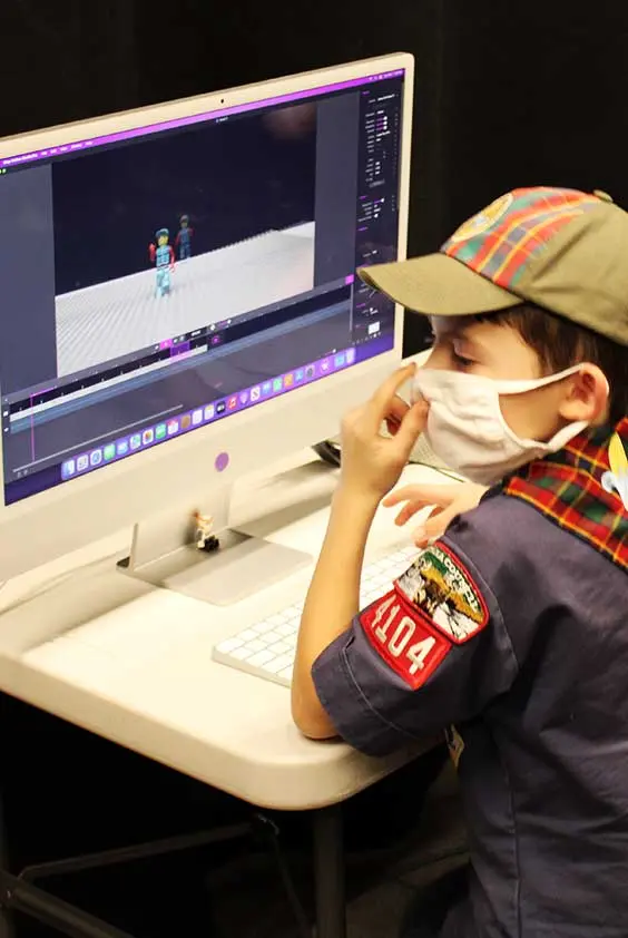 A boy wearing a face mask in front of a computer.