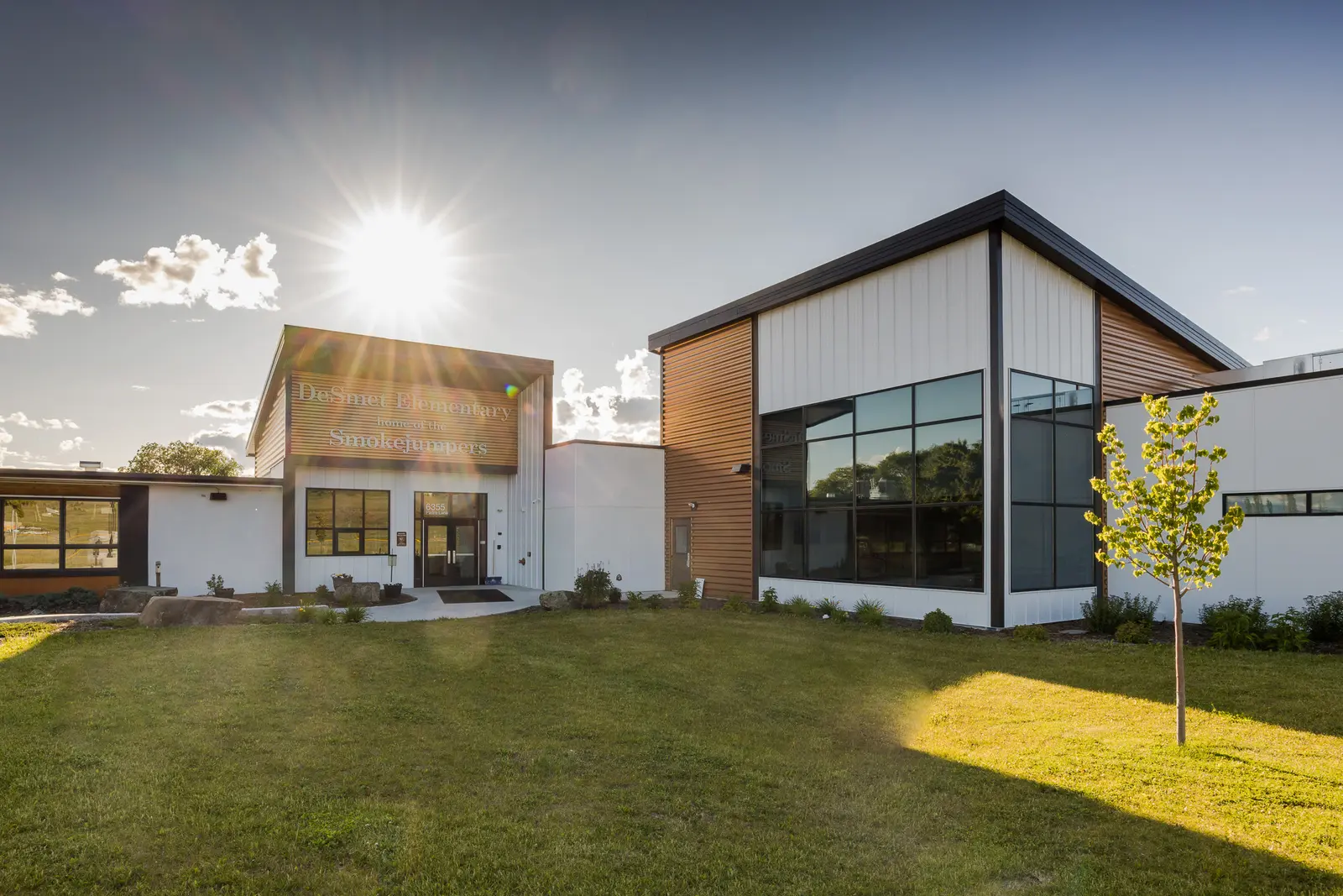 A modern school building stands under a bright sun.