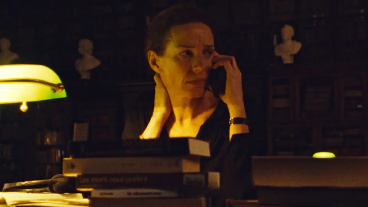 A woman talks on a telephone in a room filled with books.