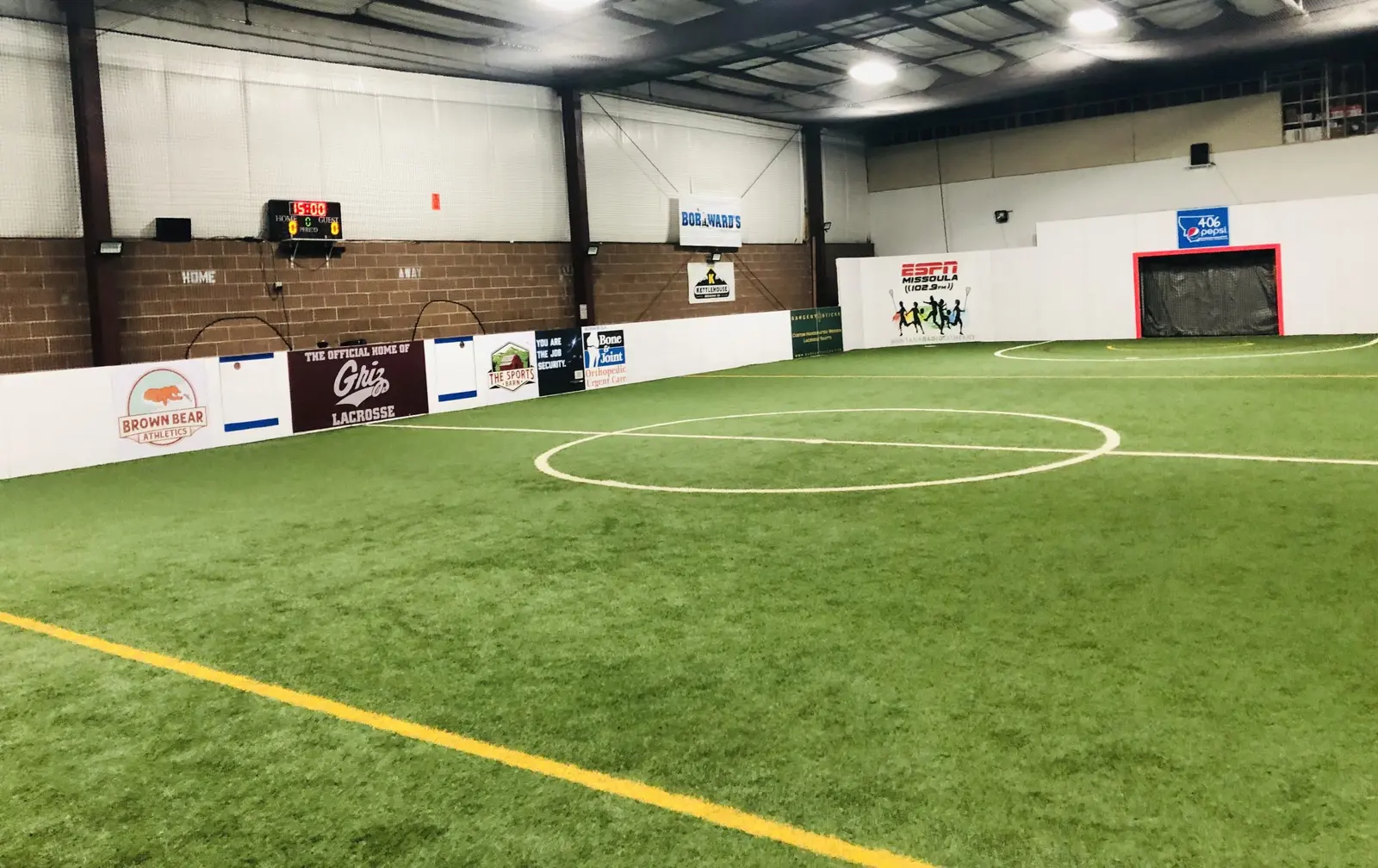 An indoor sports facility featuring artificial turf and various advertisements along the walls.