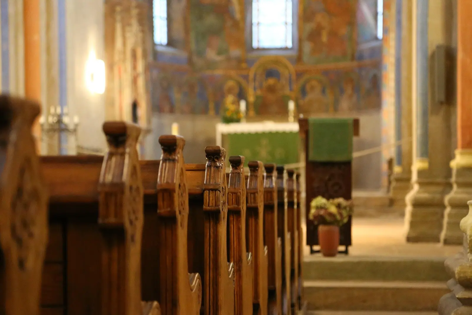 A view looking down a row of wooden pews toward the altar in a church.