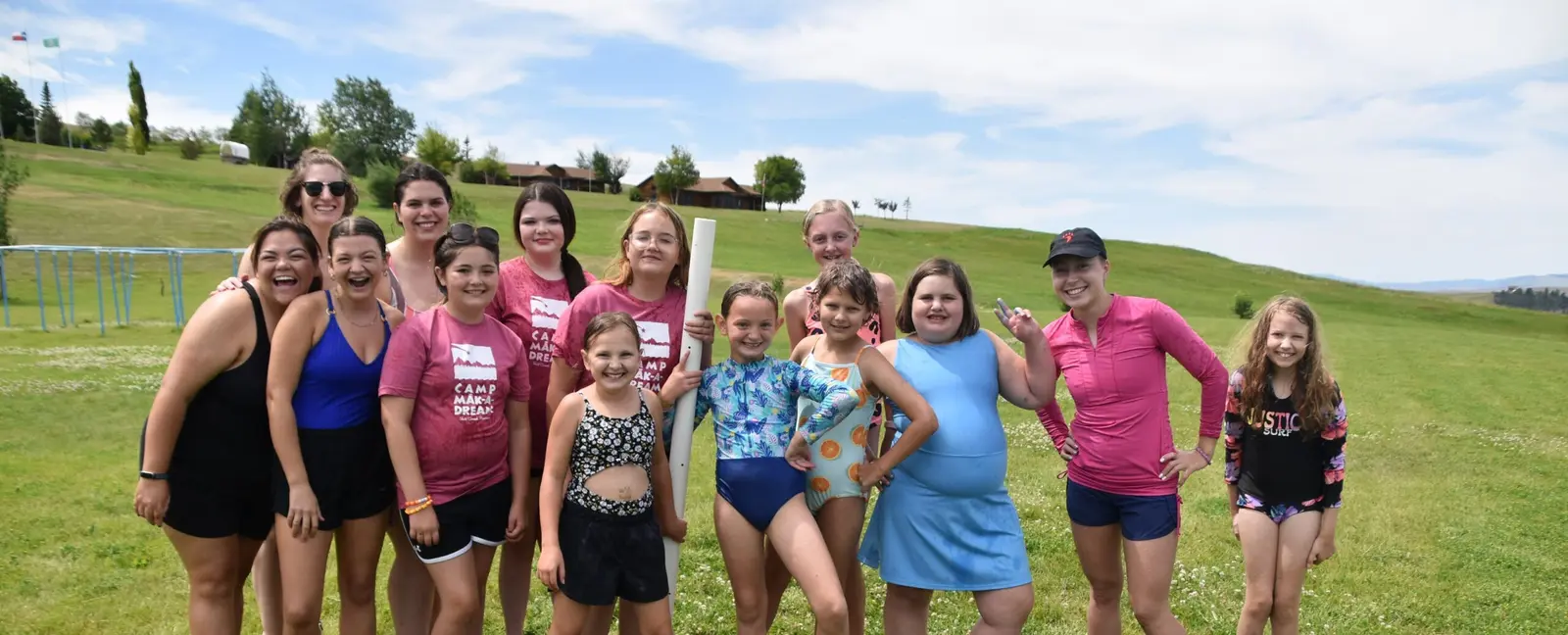 A group of children and young adults pose together in a grassy field.