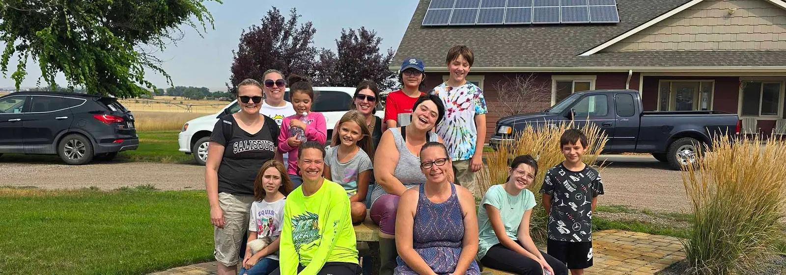 A group of adults and children are gathered outdoors in front of a building.