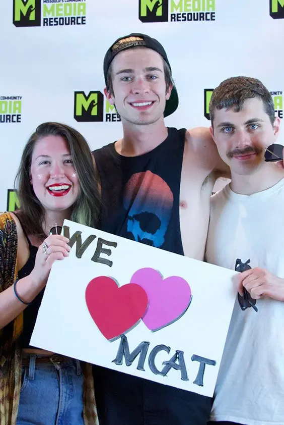 Three people (one girl on the left, two guys on the right) holding up a sign that says we love MCAT.