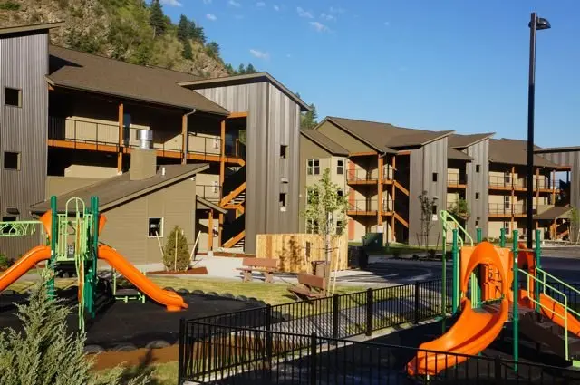 An outdoor playground area sits in front of multi-story apartment buildings.