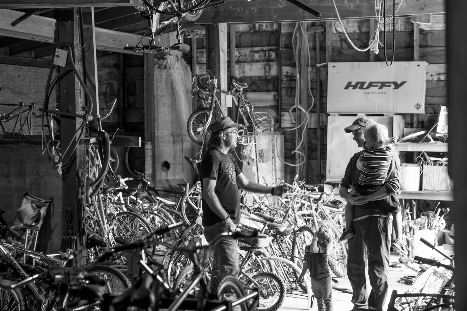 Two adults talk with children in a workshop crowded with bicycles.