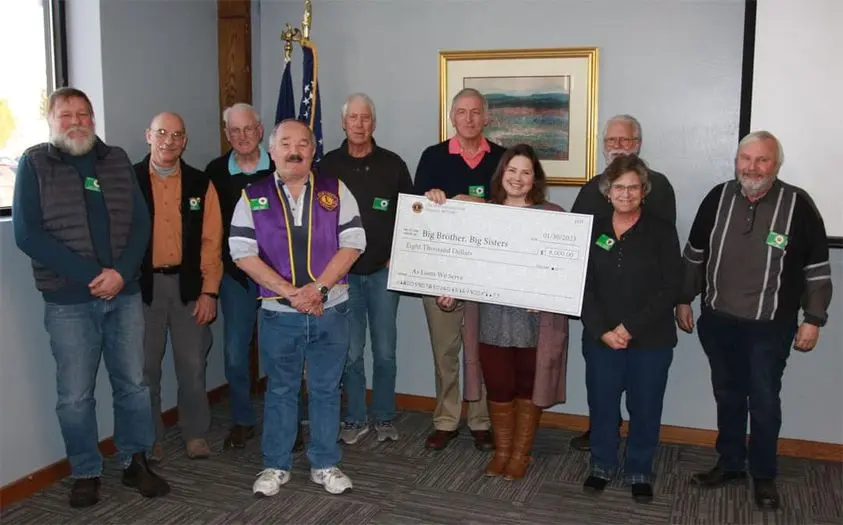 A group of people are gathered together holding a large donation check.