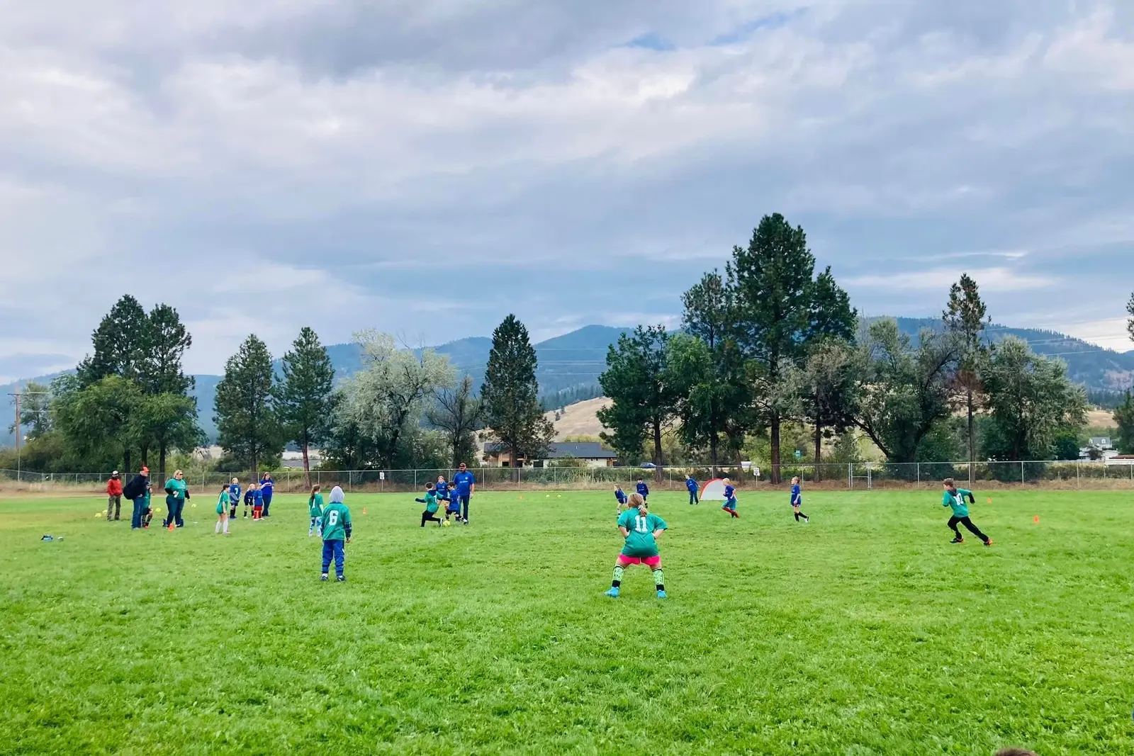 A group of children plays soccer on a field with an instructor present.